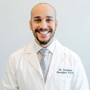 A smiling man in a dentists jacket.