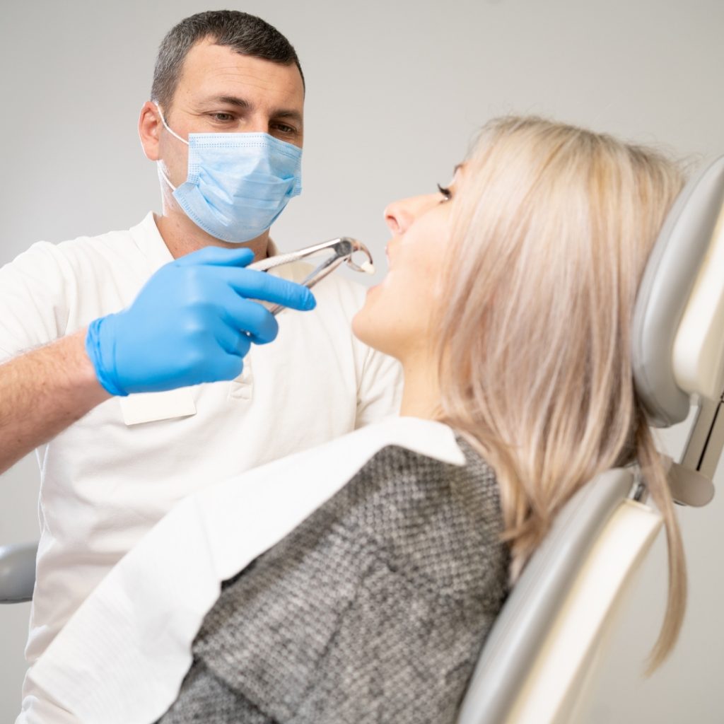 Dentist using surgical pliers to remove a decaying tooth. Modern dental clinic