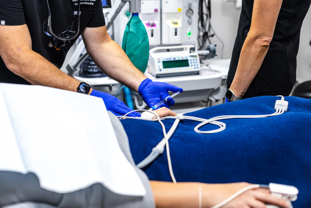 Dentist placing an IV line for a sedated patient covered with a blanket