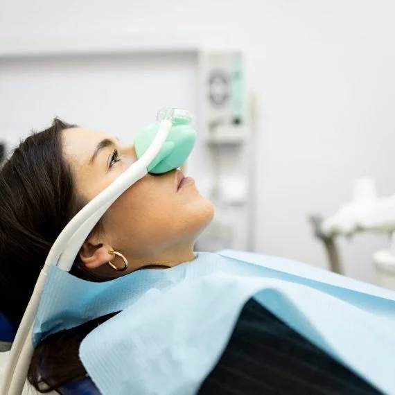 Dental patient receiving nasal sedation mask in dental chair during clinical procedure